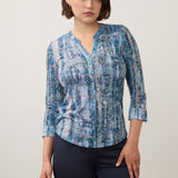 Woman wearing a printed blue top with blue pants on a light back ground.