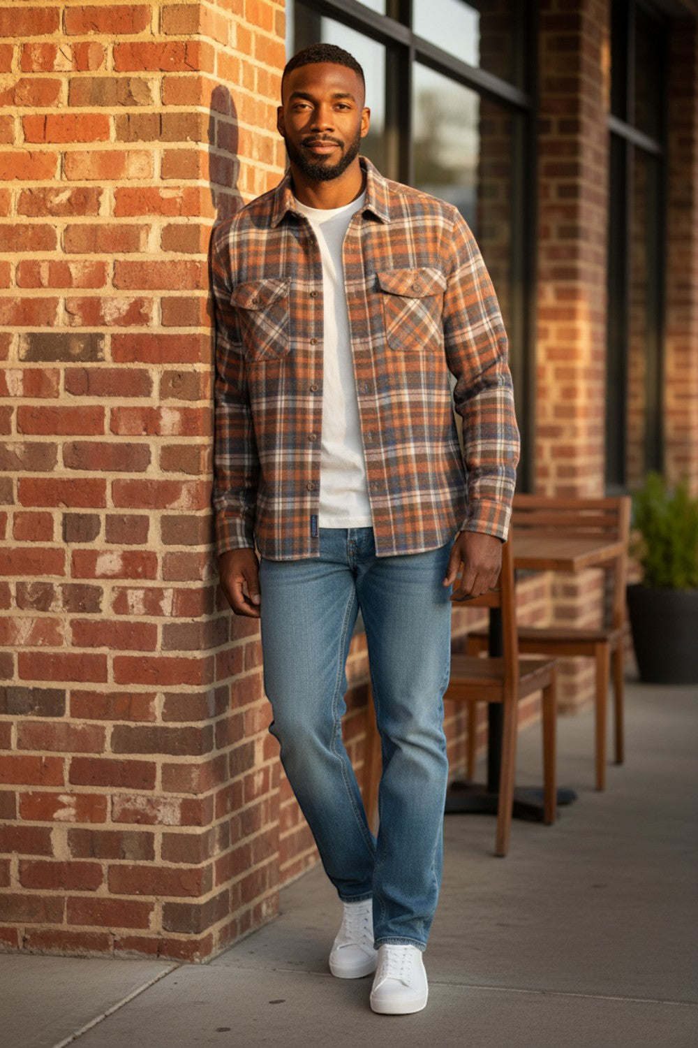 Broderick's Clothing Co. model wearing a Johnston & Murphy heathered plaid woven shirt with jeans against a brick wall.