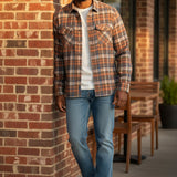 Broderick's Clothing Co. model wearing a Johnston & Murphy heathered plaid woven shirt with jeans against a brick wall.