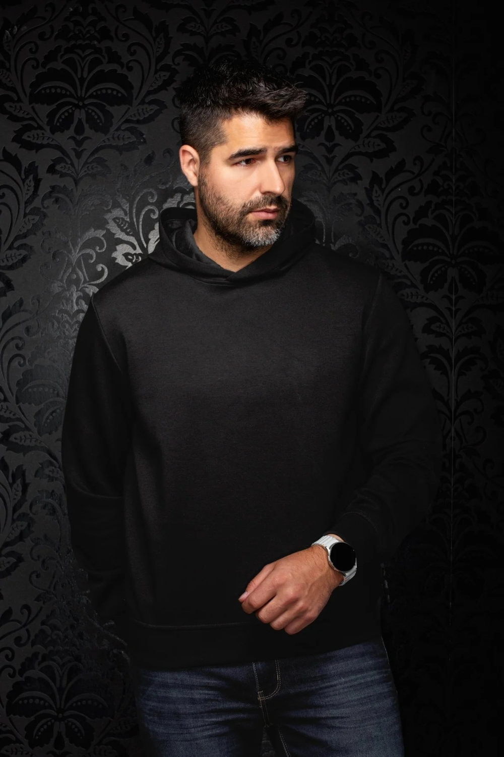Broderick's Clothing Co. Au Noir KAIZEN black pullover hoodie worn by a man against a dark patterned wallpaper