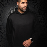 Broderick's Clothing Co. Au Noir KAIZEN black pullover hoodie worn by a man against a dark patterned wallpaper