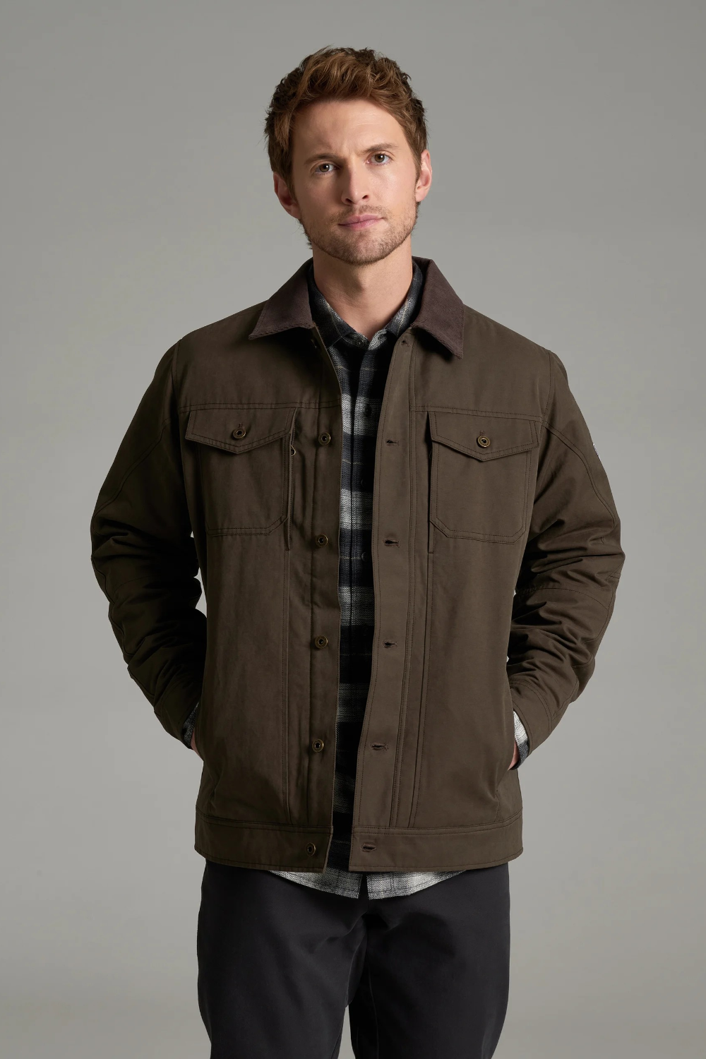 Broderick's Clothing Co. KÜHL MAVERICK brown canvas jacket with fleece lining worn by a man on a grey background