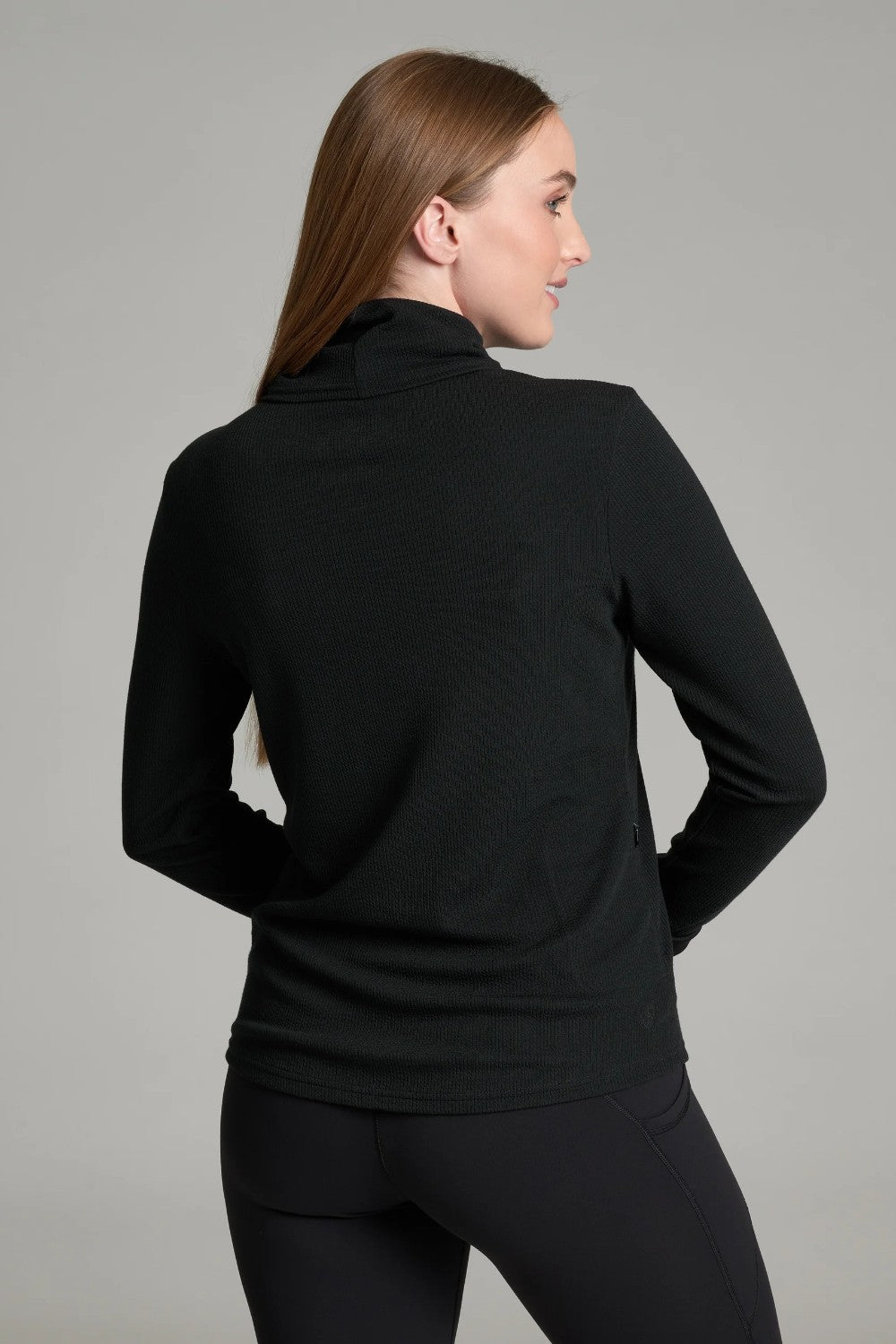 Woman wearing a black KÜHL Remi Pullover with a turtleneck and crinkle-rib texture from Broderick's Clothing Co.