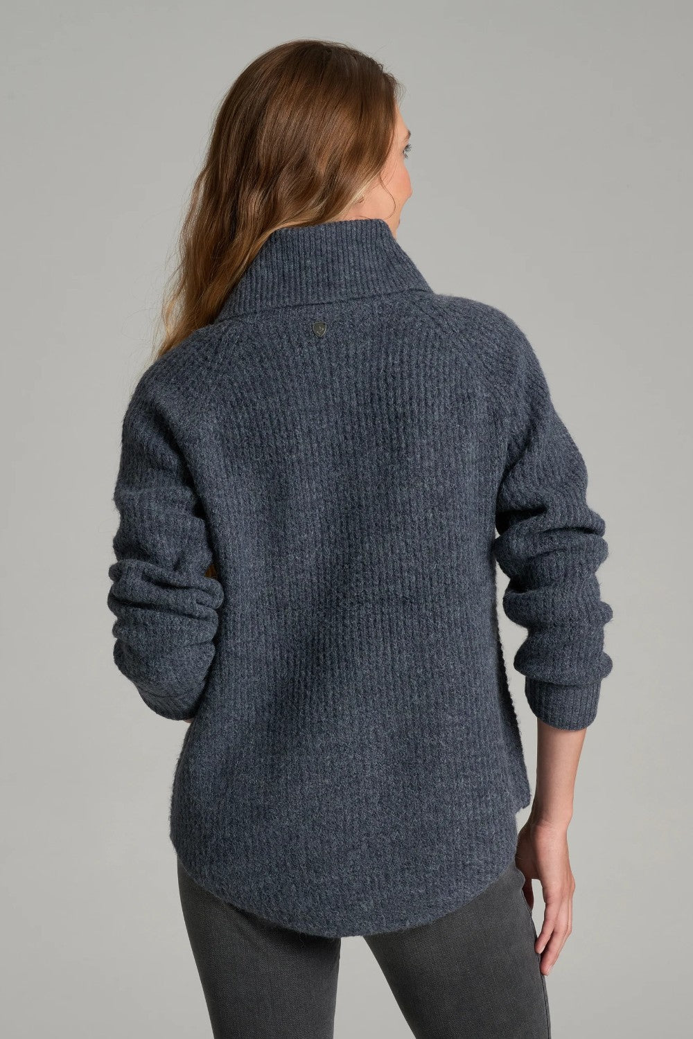 Back view of a woman wearing a Broderick's Clothing Co. KÜHL Sienna charcoal grey chunky knit sweater with cowl neck.