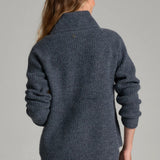 Back view of a woman wearing a Broderick's Clothing Co. KÜHL Sienna charcoal grey chunky knit sweater with cowl neck.