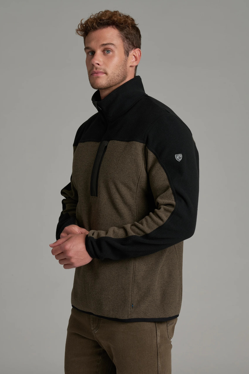 Broderick's Clothing Co. KÜHL SKORCHR fleece 1/4 zip sweater in olive and black worn by a man against a grey background