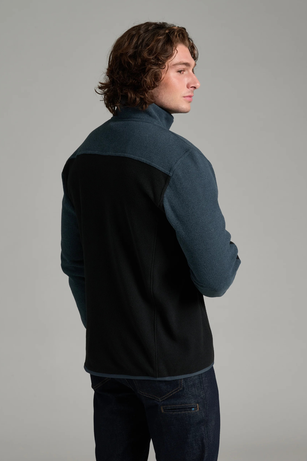 Broderick's Clothing Co. KÜHL SKORCHR fleece quarter-zip sweater in blue and black worn by a man, back view.