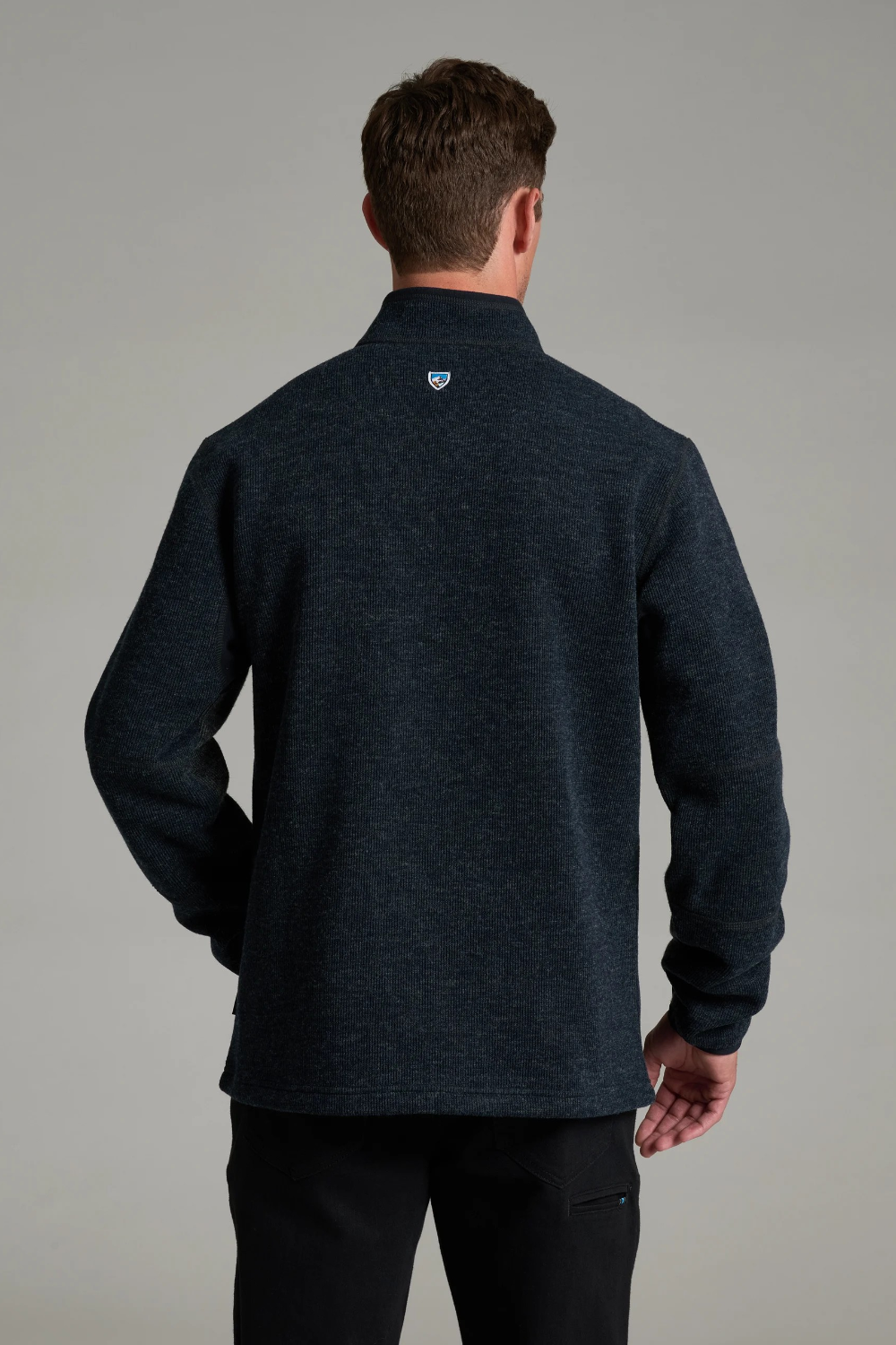 Back view of a man wearing a dark charcoal KÜHL Thor 1/4 Zip Sweater from Broderick's Clothing Co.