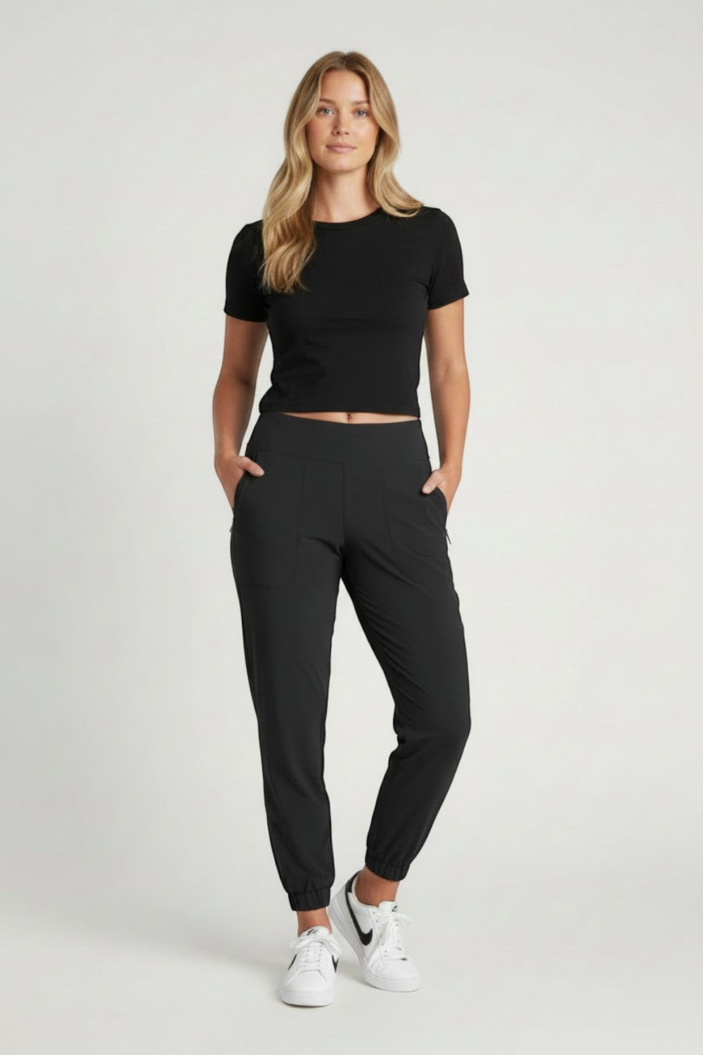 Broderick's Clothing Co. KÜHL Vantage black lined jogger pants on a woman wearing a black t-shirt and white sneakers.