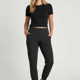 Broderick's Clothing Co. KÜHL Vantage black lined jogger pants on a woman wearing a black t-shirt and white sneakers.