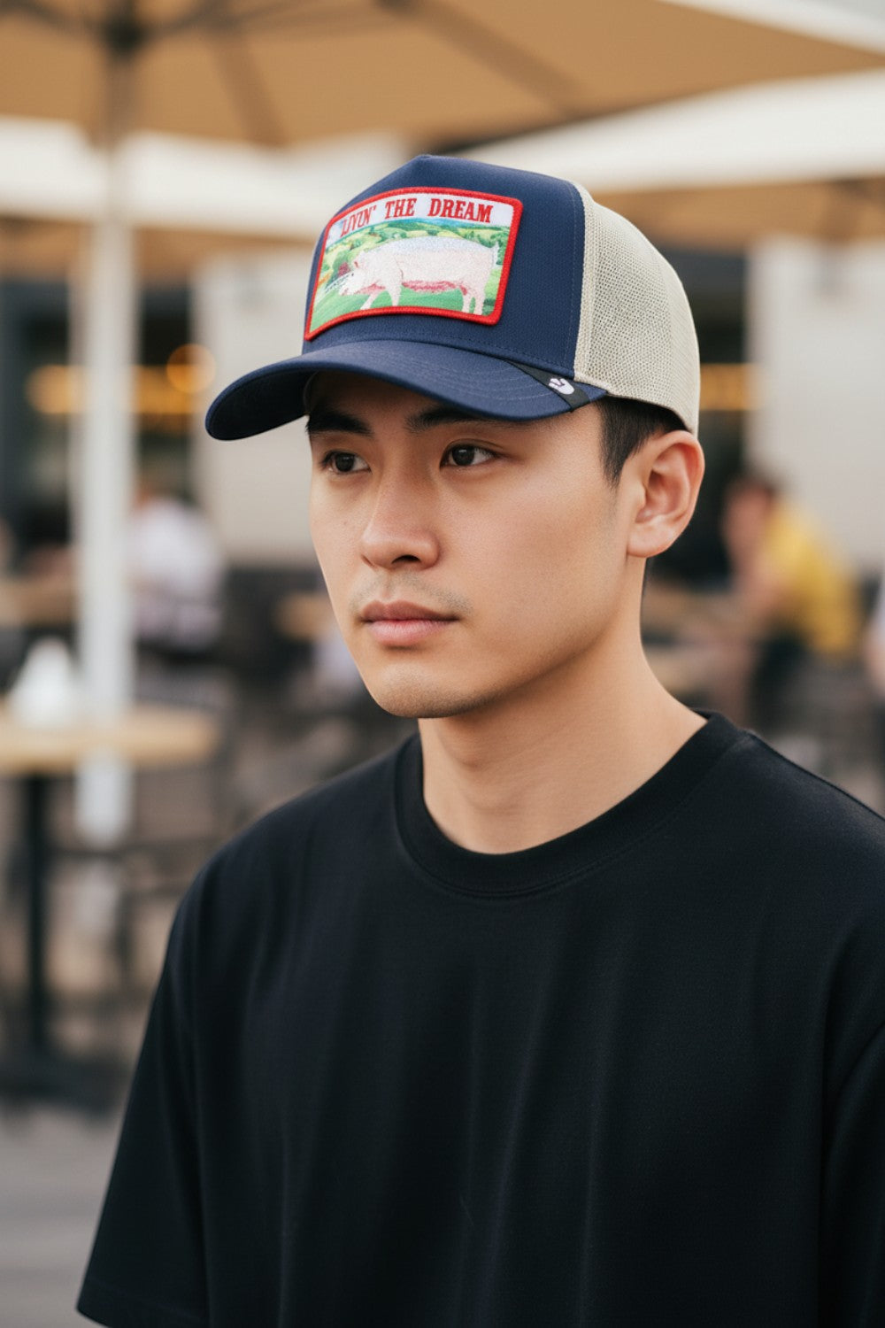 A man wearing a Broderick's Clothing Co. Goorin Bros. LIVIN' THE DREAM navy and beige mesh trucker hat.
