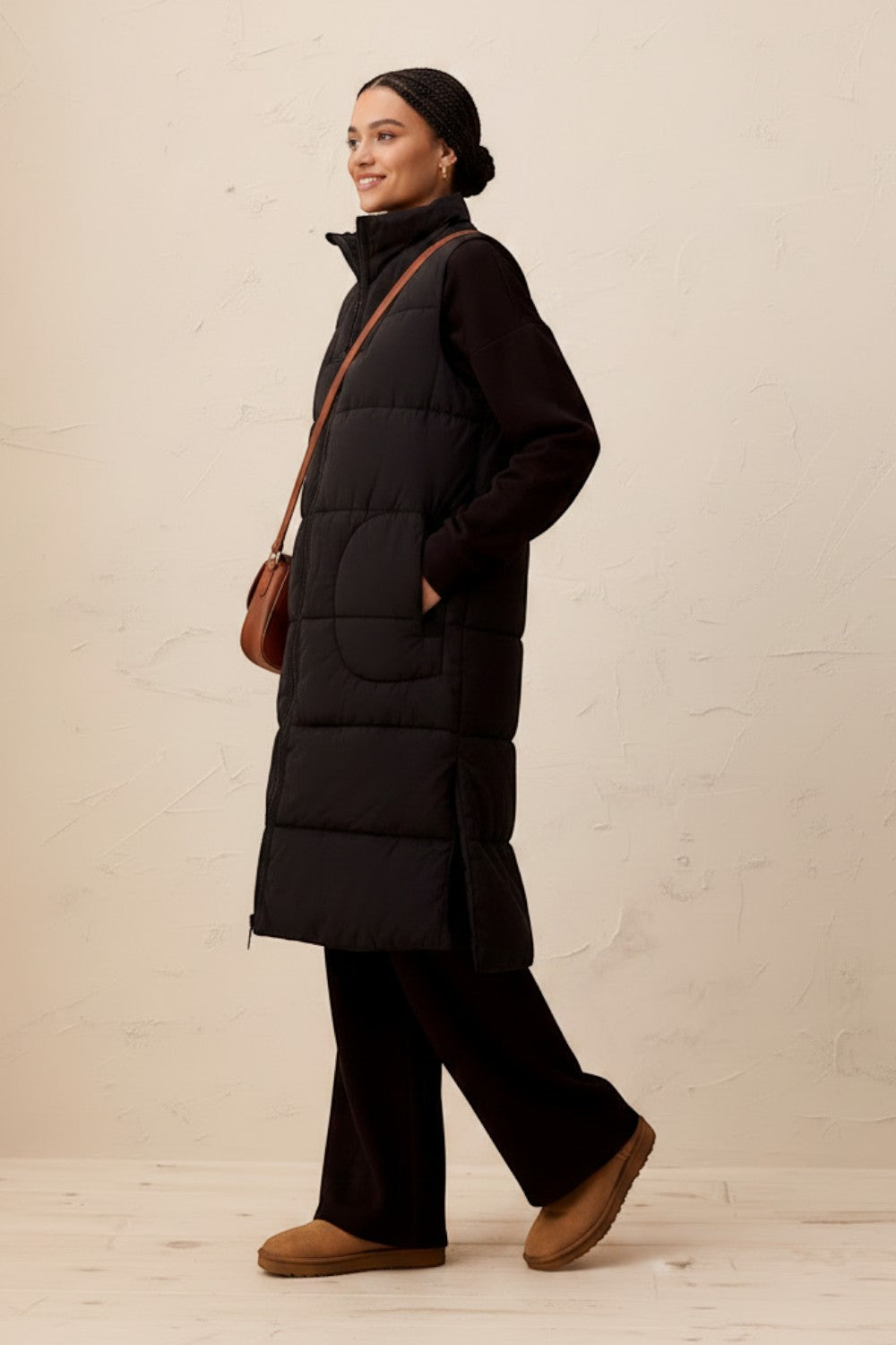 Broderick's Clothing Co. long black quilted vest with zip-front, worn by a model over a matching black outfit.