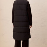 Back view of a model wearing a Broderick's Clothing Co. black longline quilted vest over a matching sweater.