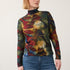 Broderick's Clothing Co. long sleeve mock neck top with a bold multi-colored leaf print worn with blue jeans.