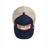 Broderick's Clothing Co. navy and beige trucker hat featuring a Livin' The Dream pig patch on the front panel.