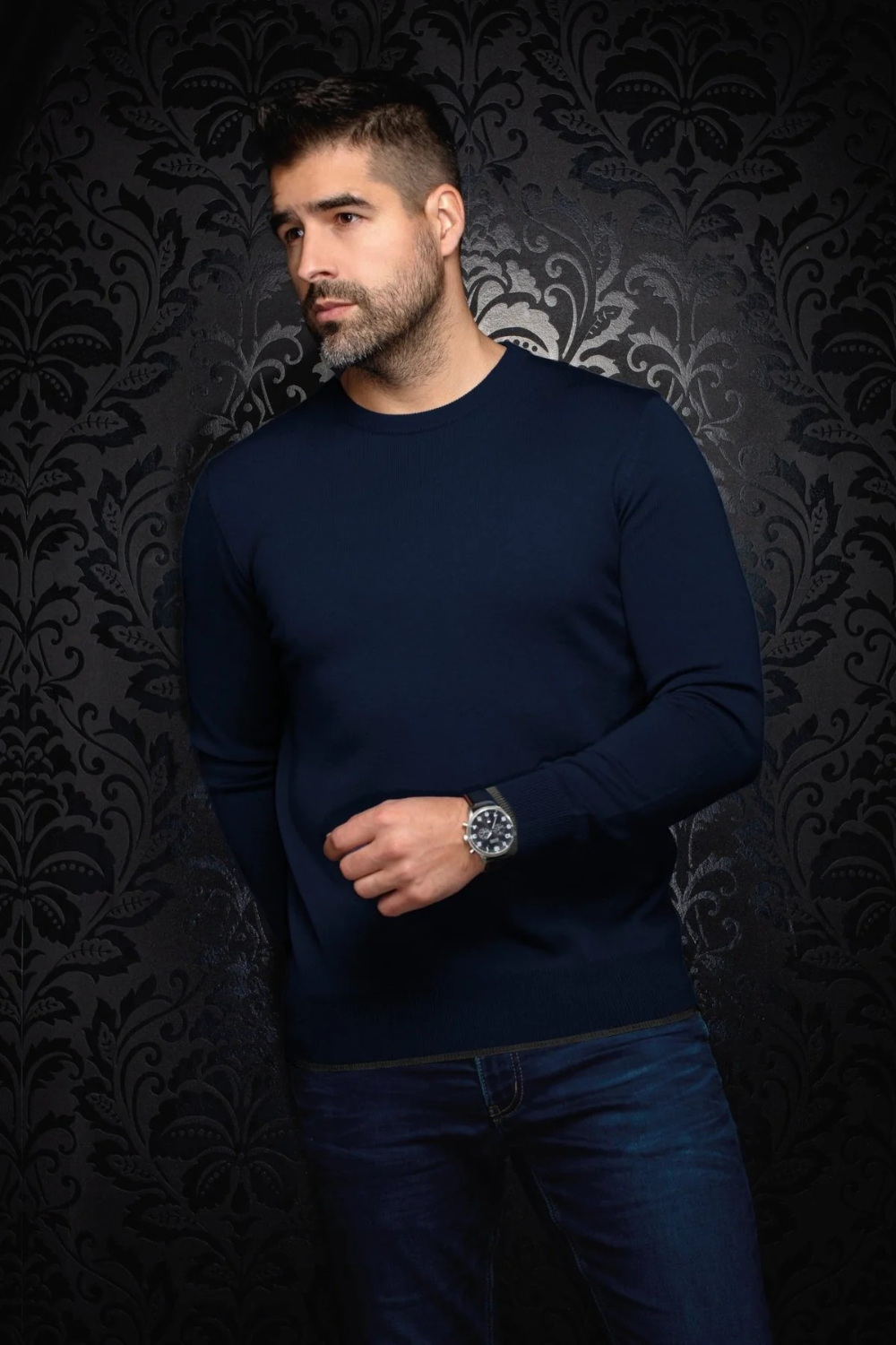 Broderick's Clothing Co. navy blue Au Noir LACAUNE cashmere crew neck sweater worn by a man against damask wallpaper