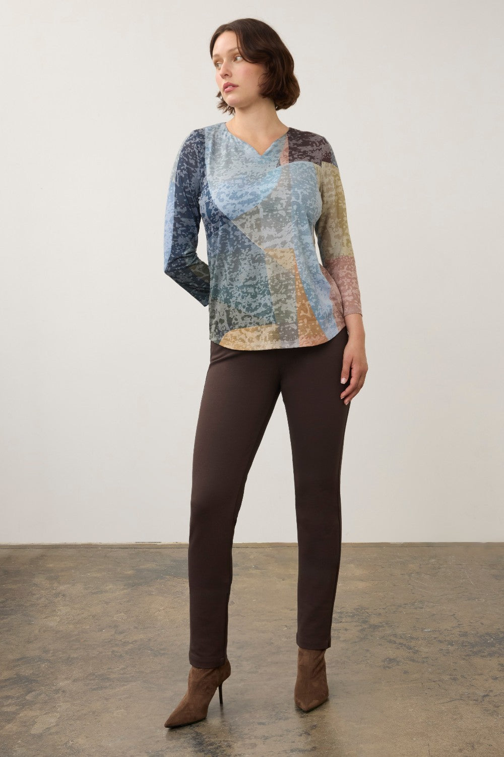 Broderick's Clothing Co. 3/4 sleeve notch neck top featuring a multi-colored geometric pattern worn with brown pants.