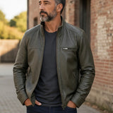 Broderick's Clothing Co. olive green leather bomber jacket with stand-up collar worn by a man outdoors.