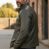 Broderick's Clothing Co. olive green leather bomber jacket with stand-up collar worn by a man in a side profile view.