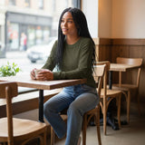 Model wearing a Broderick's Clothing Co. Shannon Passero Zoya olive green long-sleeve top with jeans in a cafe