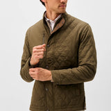 Broderick's Clothing Co. olive green diamond-quilted snap jacket with suede trim worn by a man on a white background.