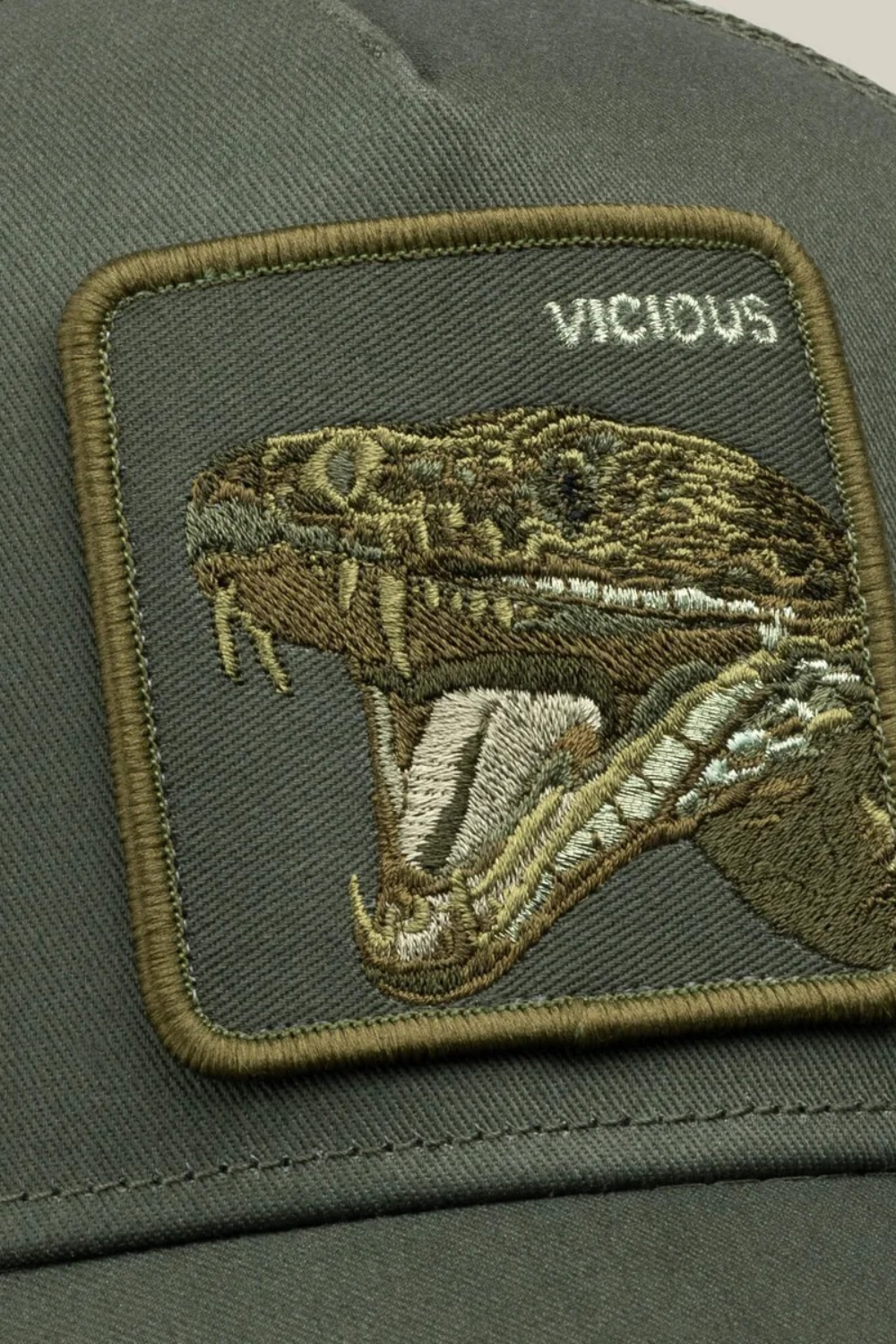 Broderick's Clothing Co. olive trucker hat featuring a detailed embroidered patch of a vicious snake head
