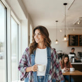 Broderick's Clothing Co. model wearing a plum and teal plaid kimono-style cardigan with denim trim in a cafe.