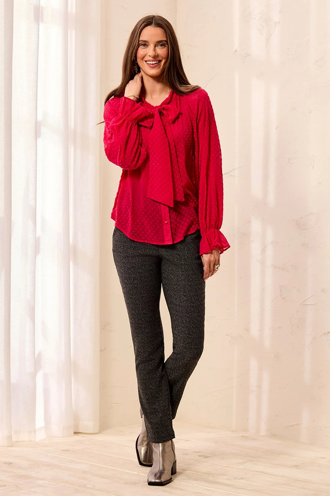 Broderick's Clothing Co. red polka dot crinkle chiffon blouse with bow-tie neck and ruffled cuffs on a smiling model.