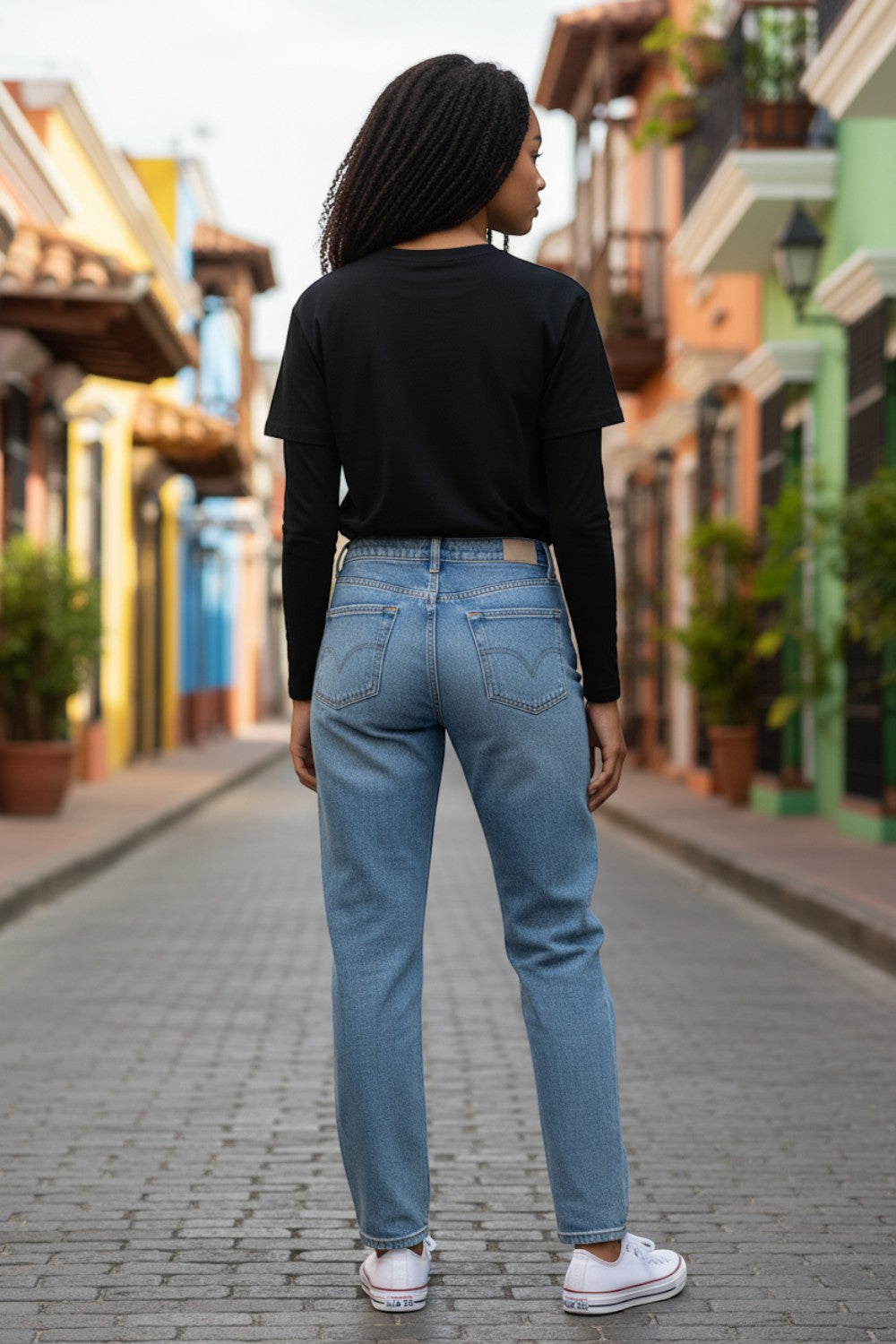 Model wearing Broderick's Clothing Co. Shannon Passero Zoya black long-sleeve top and blue jeans on a city street