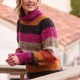 Broderick's Clothing Co. woman wearing a multi-colored striped bouclé turtleneck sweater on a balcony