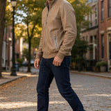 Broderick's Clothing Co. tan lamb leather jacket with stand-up collar worn by a man on a cobblestone street.