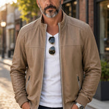 Broderick's Clothing Co. tan lamb leather jacket with stand-up collar and ribbed cuffs worn by a man on a city street