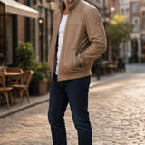 Broderick's Clothing Co. tan lamb leather jacket with stand-up collar worn by a man on a cobblestone street.