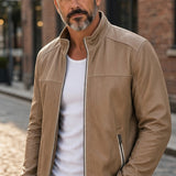 Broderick's Clothing Co. tan lamb leather jacket with stand-up collar and ribbed cuffs worn by a man on a city street.