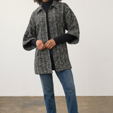 Model wearing a Broderick's Clothing Co. black and white tweed poncho jacket with wide sleeves over blue jeans.