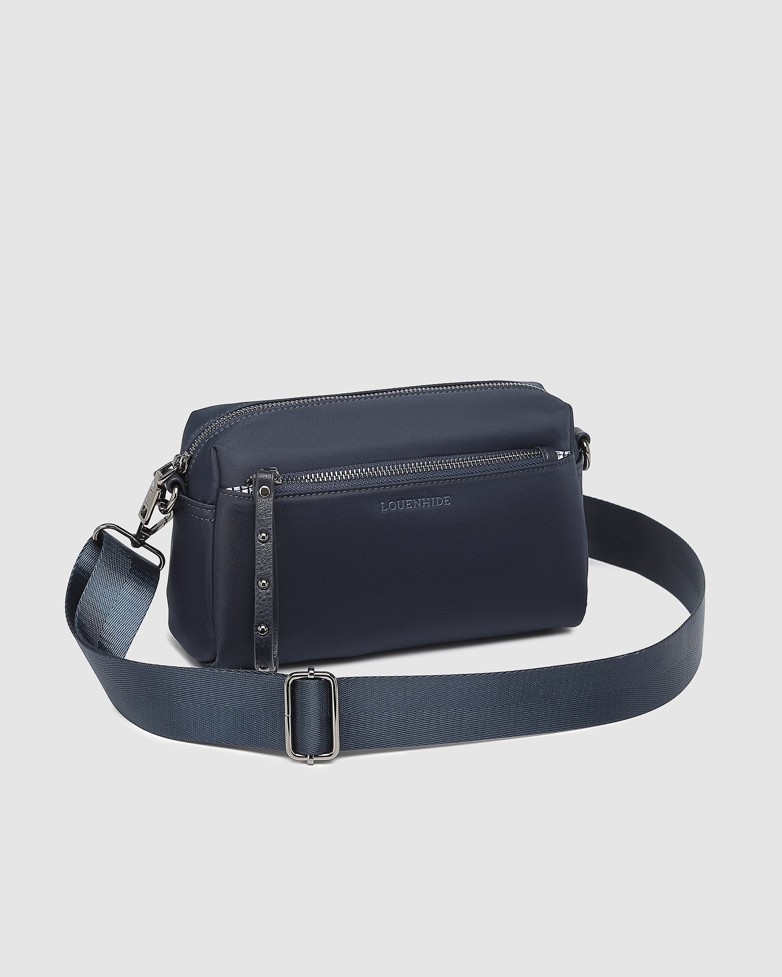 The Louenhide Rowie Nylon Crossbody Bag is the practical, everyday accessory you've been searching for. Embrace an organized dream with multiple internal and external pockets and a stylish matching cardholder. The Rowie's minimalist&nbsp;design is enhanced by the gunmetal detailing - adding the perfect touch of contemporary edge to its classic silhouette.&nbsp; Whether you're exploring the city or embarking on an adventure, this crossbody bag effortlessly complements your capsule wardrobe. 