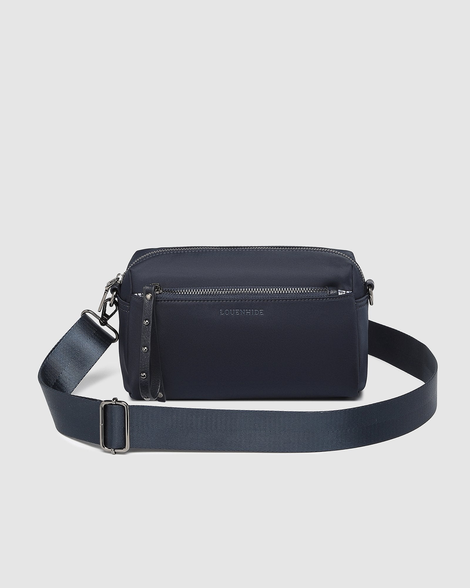 The Louenhide Rowie Nylon Crossbody Bag is the practical, everyday accessory you've been searching for. Embrace an organized dream with multiple internal and external pockets and a stylish matching cardholder. The Rowie's minimalist&nbsp;design is enhanced by the gunmetal detailing - adding the perfect touch of contemporary edge to its classic silhouette.&nbsp; Whether you're exploring the city or embarking on an adventure, this crossbody bag effortlessly complements your capsule wardrobe. 