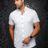 Man wearing a white shirt with black buttons against a dark patterned wall