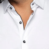 Close-up of a white shirt with black buttons on a plain background