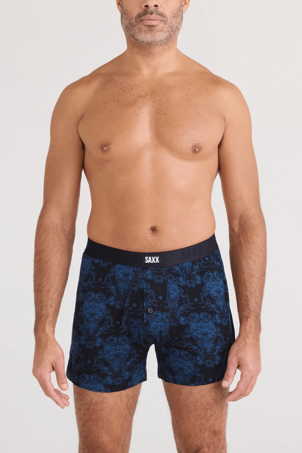 Man wearing navy blue patterned boxer briefs on a white background