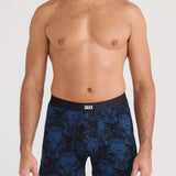 Man wearing navy blue patterned boxer briefs on a white background