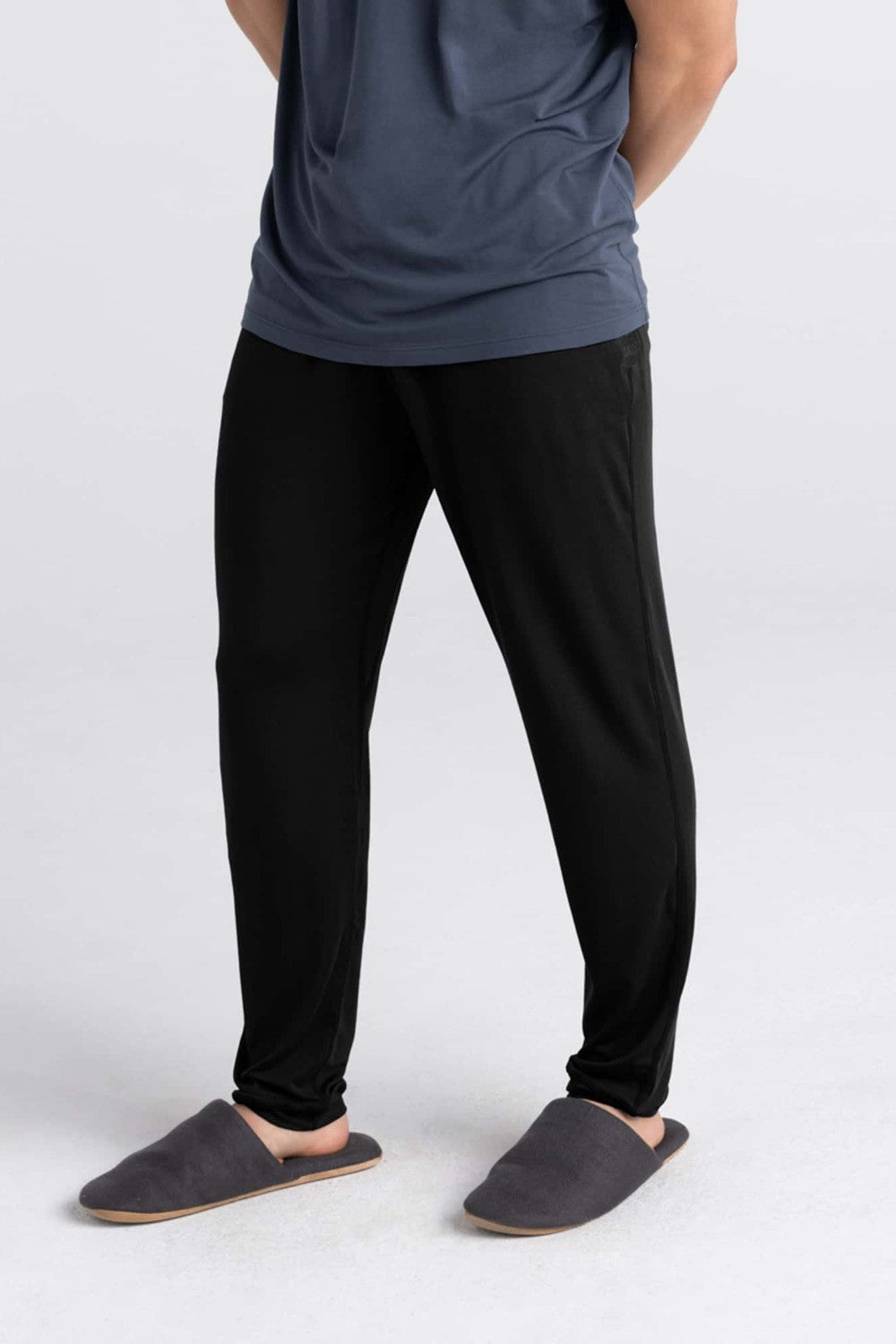 Person wearing black pants and gray shoes on a white background