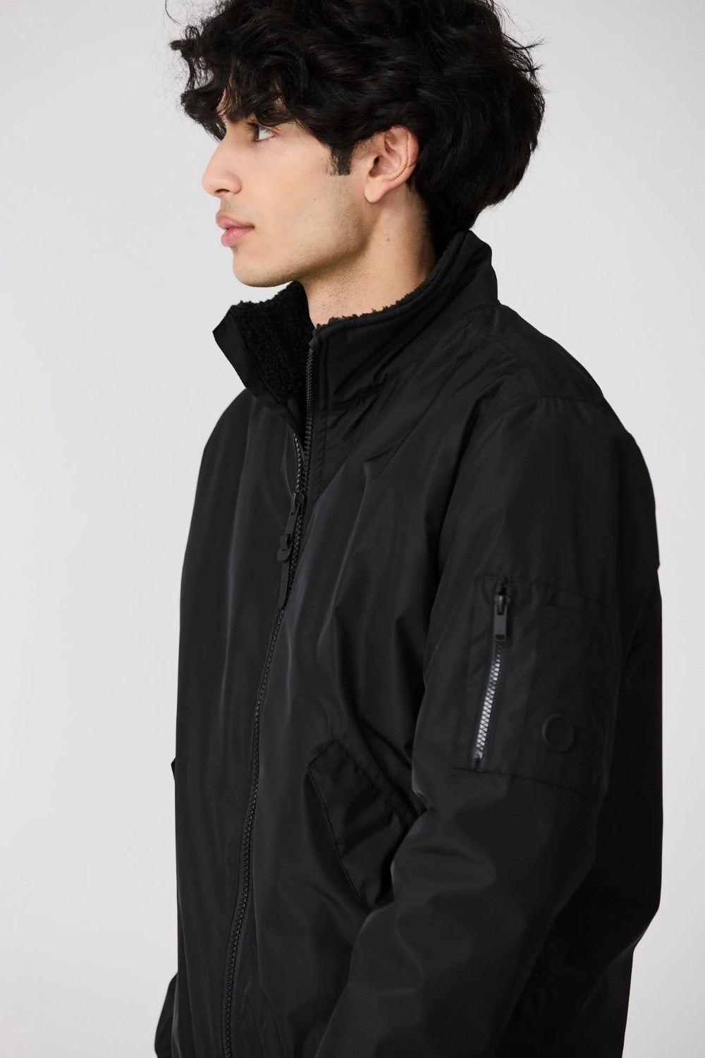 Person wearing a black jacket against a white background