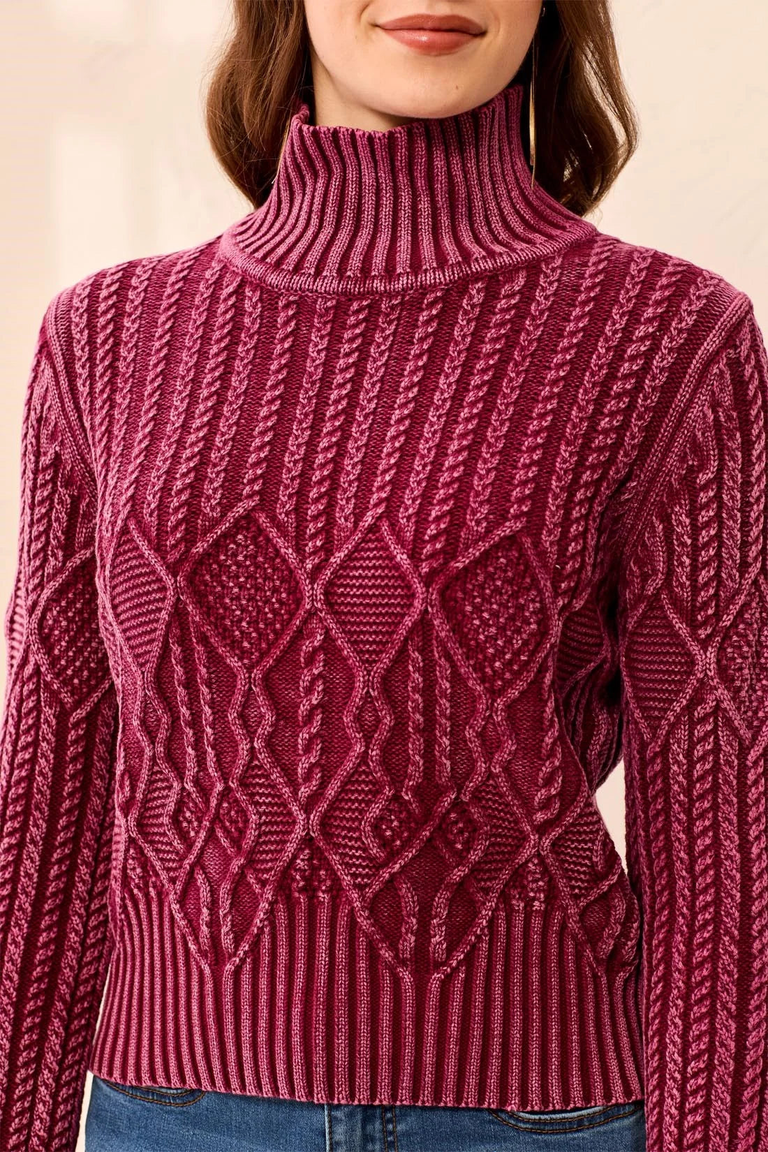 Close-up of a person wearing a maroon sweater with a geometric pattern on a beige background