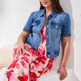 Woman wearing a denim jacket over a floral dress against a white background