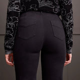 Person wearing black pants with a patterned top against a gray background