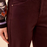 Close-up of a person wearing dark burgundy high-waisted jeans with a patterned knit sweater partially visible at the top.