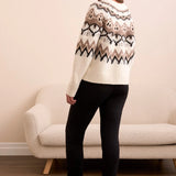 Woman wearing a patterned sweater standing in a room with a beige sofa.