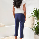 Woman wearing a white shirt with navy capris on a white background