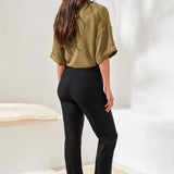 Woman wearing green top with black ankle pants on a white background